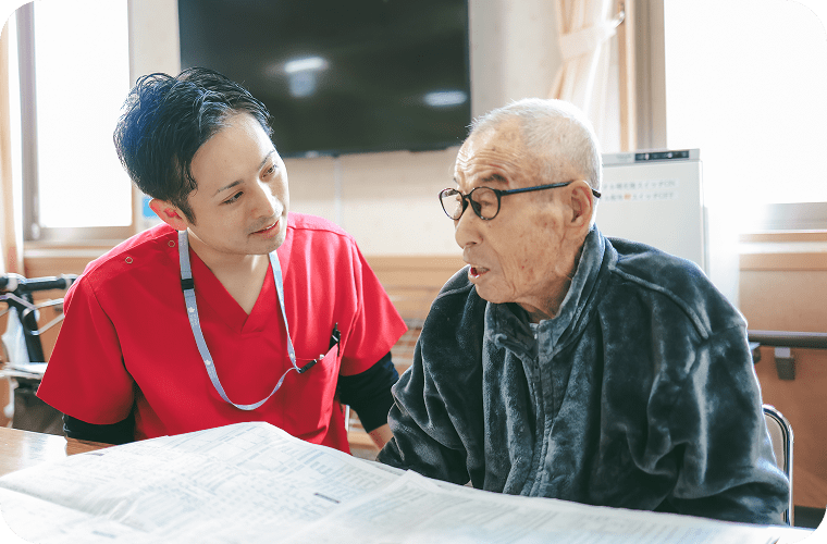 新聞を読む患者さんと介助スタッフ